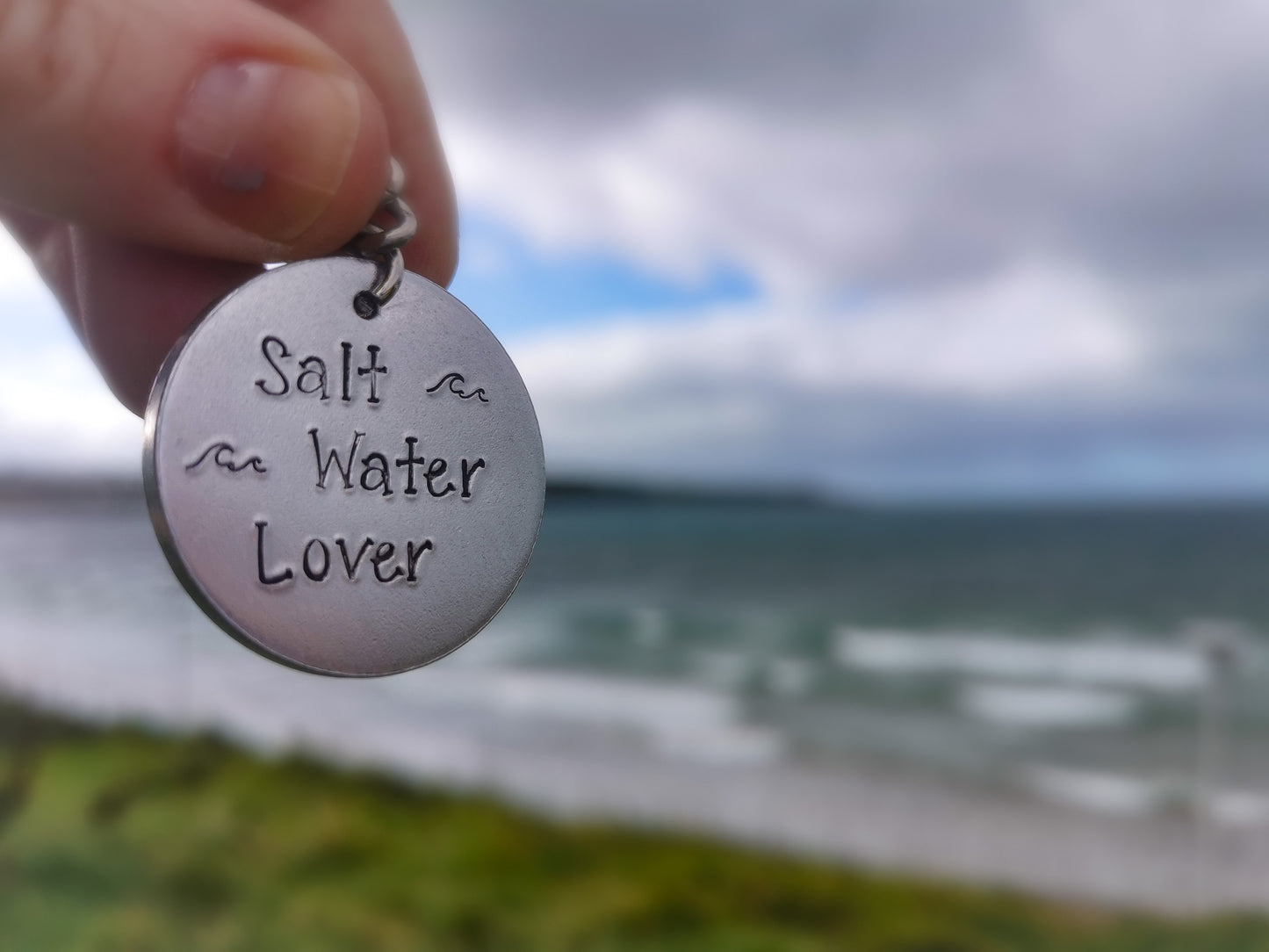 A silver coloured aluminium disc keyring, handstamped with the words Salt Water Lover