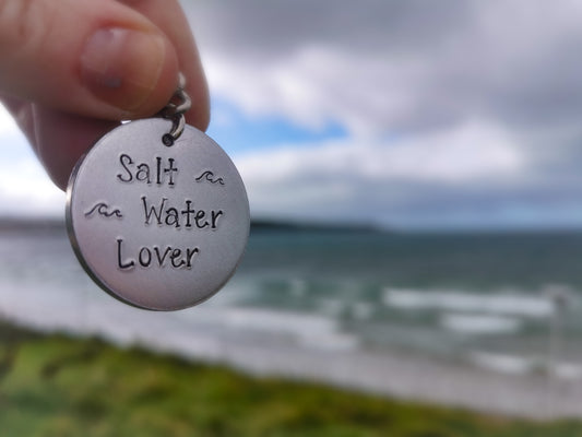 A silver coloured aluminium disc keyring, handstamped with the words Salt Water Lover